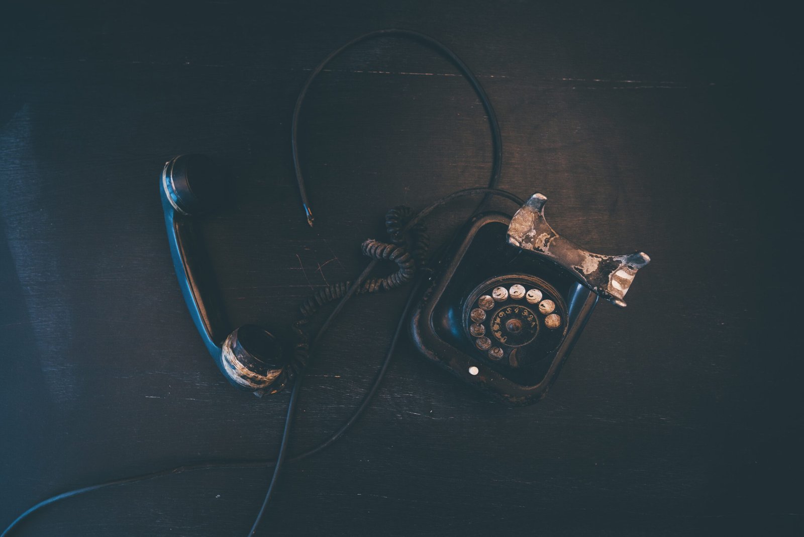 Black vintage landline telephone, old and weathered. Broken communication concept.